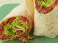 Zwei saftige wraps zum mitnehmen, gefüllt mit knackigem Salat, Tomaten und einer würzigen Fleischfüllung. Perfekt für unterwegs!