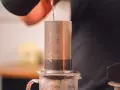 Przygotowanie kawy metodą aeropress cold brew. Woda powoli spływa do cylindra z kawą.