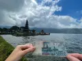 Ręka trzyma banknot 50 000 rupii na tle świątyni na wodzie. To symboliczne, że wiza turystyczna na Bali jest w zasięgu ręki!