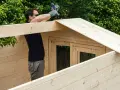 Hombre montando una caseta de madera. La madera clara y resistente es la mejor madera para exterior.
