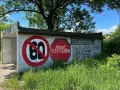 Niedziela, dzień cwel, pod drzewem, z zakazem 60 i napisami na ścianie.