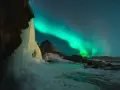 Lodowy wodospad i zorza polarna na nocnym niebie. Islandia w styczniu, magiczny widok.