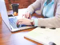 Kobieta pisze na laptopie, obok leży notatnik. Czy wezwanie do zapłaty można wysłać mailem?