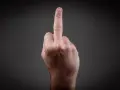 Eine Hand zeigt den Mittelfinger. Dies kann als Geste der Ablehnung oder als Zeichen der Rebellion gesehen werden, die eine Strafe nach sich ziehen kann.