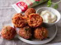Was sind Arancini? Knusprig frittierte Reisbällchen mit geschmolzenem Käse, serviert mit einer cremigen Dip-Sauce.