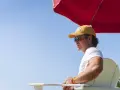 Ein Rettungsschwimmer mit gelber Kappe und Sonnenbrille wacht am Pool des **summer camp**.