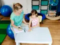 Terapeuta ocenia reakcje dziecka podczas badania sensorycznego, sprawdzając jego wrażliwość dotykową i propriocepcję.