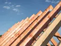 Drewniane krokwie dachowe pod błękitnym niebem. Sprawdź aktualną krokwie dachowe cenę i zaplanuj budowę.