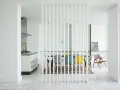 Elegante solución para dividir salón en dos ambientes. Cocina moderna y comedor con sillas de colores, separados por una celosía blanca.