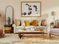 Acogedor salón con sofá, sillones y mesa de centro. Destaca una **gama colores cálidos** en cojines, mantas y decoración otoñal.