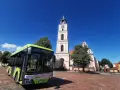 Zielony autobus MZK Chodzież czeka na pasażerów pod wieżą kościoła. Sprawdź mzk chodzież rozkład jazdy i zaplanuj podróż!