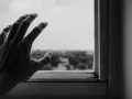 Dłoń oparta o brudną szybę, symbolizująca strach przed ludźmi i izolację od świata zewnętrznego.