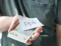Dłoń trzyma banknoty i karteczkę z napisem "ppk". Jak sprawdzić swoje oszczędności?