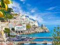 Costiera Amalfitana, un sogno di **Italia in moto** tra limoni e mare blu. Case bianche aggrappate alla roccia, un borgo pittoresco.