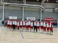 Drużyna w strojach biało-czerwonych, w tym Filip Jankowski, stoi na parkiecie hali sportowej.