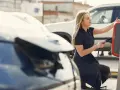 Kobieta ładuje samochód elektryczny na stacji ładowania.