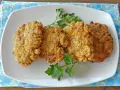 Cuatro filetes rusos dorados y crujientes servidos en un plato blanco con perejil.