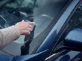 En hand pekar på ett stenskott på vindrutan. En olycklig påminnelse om vägens faror.