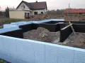 Budowa domu: jak ocieplić fundament styropianem. Widoczne elementy izolacji fundamentów, zbrojenia i ziemia.