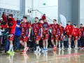 Drużyna kwidzyn piłka ręczna w czerwonych strojach wchodzi na halę, pozdrawiając kibiców.