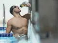 Un nageur en bonnet et lunettes boit dans une bouteille, prêt à apprendre comment nager.