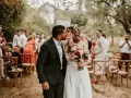 Un couple s'embrasse lors d'une cérémonie laïque exemple en plein air. Les invités sont assis sur des chaises en bois dans un cadre verdoyant.