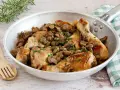 Delizioso pollo con funghi in padella, guarnito con prezzemolo fresco e accompagnato da rosmarino.