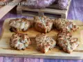 Sei crostini salsiccia e stracchino dorati e filanti, pronti per essere gustati su un tagliere di legno.