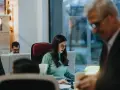 Kobieta w okularach skupiona na pracy przy biurku, przykład etyki zawodowej w nowoczesnym biurze.