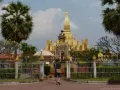 Złota stupa Pha That Luang, symbol stolicy w Wientianie, otoczona palmami i zielenią.