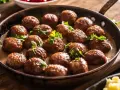 Une poêle remplie de boulettes de viande savoureuses, nappées de sauce crémeuse et garnies de persil frais. Une invitation à découvrir cette recette de boulette de viande.
