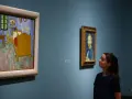 Deux femmes contemplent des tableaux. À gauche, la chambre de Van Gogh, une œuvre iconique dont le prix tableau peinture à l'huile fascine.
