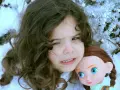 Ein Kind mit dunklen Haaren hält eine Puppe im Schnee. Das Kind sieht besorgt aus, als ob mein Kind Angst vor mir hätte.