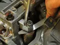 Mechanik reguluje zawory w silniku, używając śrubokręta i szczelinomierza.