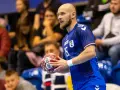 Mateusz Jachlewski, szczypiornista w niebieskiej koszulce z numerem 15, trzyma piłkę do piłki ręcznej.