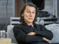 Krzysztof Warlikowski, reżyser teatralny, w czarnym garniturze, siedzi na kanapie. Jego życie prywatne budzi zainteresowanie.