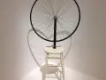 Roue de vélo fixée sur un tabouret, une œuvre emblématique de Marcel Duchamp, projetant une ombre fascinante.