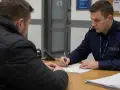 Policjant w mundurze spisuje dokumenty. Dowiedz się, jak sprawdzić status sprawy na policji, aby uzyskać potrzebne informacje.