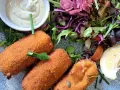 Croquetas doradas y crujientes con ensalada fresca, salsa y limón.