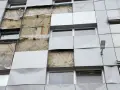 Facciata di un edificio con pannelli rimossi, mostrando l'isolamento. Si valuta la conducibilità termica dei materiali per l'efficienza energetica.