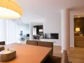 Comedor y salón modernos tras reforma piso pequeño. Mesa de madera, chimenea y mobiliario elegante.