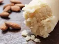 Frische Mandeln liegen neben einer Rolle Marzipan Rohmasse, bereit zum Verarbeiten.