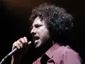 Zack de la Rocha heute, mit seinem charakteristischen lockigen Haar und einem Mikrofon in der Hand, singt leidenschaftlich auf der Bühne.