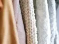 Nahaufnahme von Strickwaren in verschiedenen Pastelltönen. Die feine Struktur zeigt, dass Merinowolle fusselt, was den weichen Charakter unterstreicht.