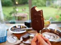 Ein abgebissener Schokoriegel, der zeigt, wie einfach es ist, Magnum Eis selber machen. Zutaten und Eisformen liegen bereit.