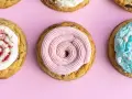 Galletas americanas decoradas con glaseado rosa, blanco con frambuesa y azul con chispas. ¡Una deliciosa receta para compartir!