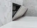 Otwarta rewizja w budownictwie, ukryta za płytkami, umożliwia dostęp do instalacji.