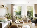 Salón con sofás, sillón, mesa de centro y alfombra de yute. La decoracion aesthetic se realza con cojines en tonos tierra y verdes, plantas y luz natural.