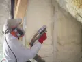 Pracownik w kombinezonie natryskuje piane pur w puszce, która zapewnia doskonałą wydajność izolacji poddasza.