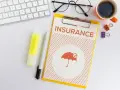 Dokument "Insurance" z parasolką, klawiatura, okulary, kawa. Planowanie ubezpieczenia zdrowotnego bez pracy.